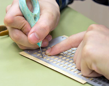 Close-up photograph of a child's hands writing with a slate and stylus